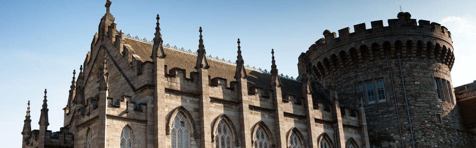 The roof of a castle includes a turret, arches, and very ornate points at the top of each spire. 
